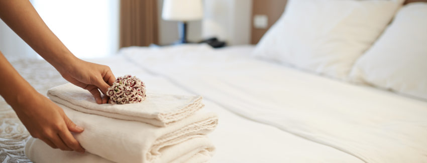 Hands of hotel maid putting flowers on the stack of towels